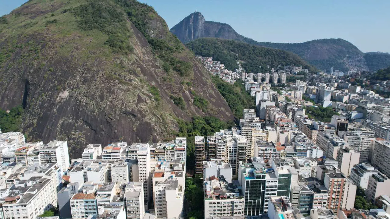 Vista dos fundos do terreno: o morro verde e os prédios de Copacabana ao longe